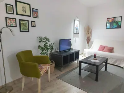 a living room with a bed and a chair and a table at Town Space Apartment Niš in Niš