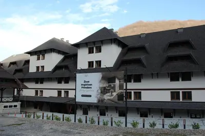 a large white building with a black roof at Kopaonik Apart Bela Reka Brzece in Brzeće