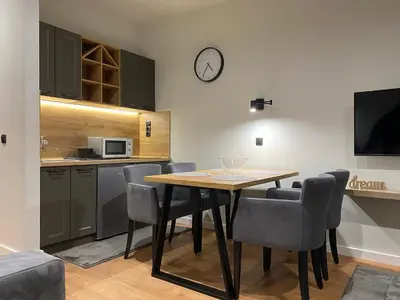 a dining room with a table and chairs and a clock at Kopaonik Apart Bela Reka Brzece in Brzeće