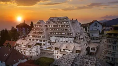a large building with the sun setting in the background at Kopaonik Zoned 2 in Kopaonik