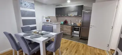 a kitchen with a table and chairs in a room at Vlyche apartment FREE PARKING in Niš