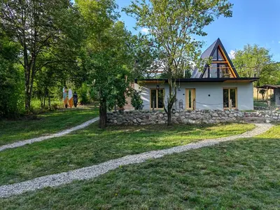 a small white house with a stone wall at Brvnara Riva in Niš