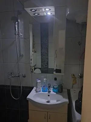 a bathroom with a sink and a shower with a mirror at Apartman sa panoramom in Kruševac