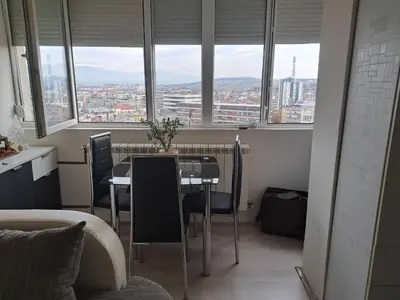 a table and chairs in a room with windows at Apartman sa panoramom in Kruševac