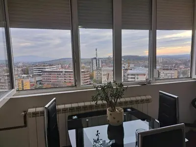 a table with a potted plant in a room with windows at Apartman sa panoramom in Kruševac