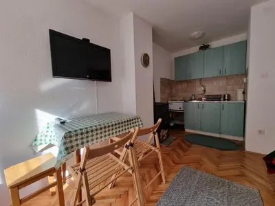 a living room with a table and a television on the wall at APARTMAN NA STAZI - Bela Reka, Kopaonik in Brzeće