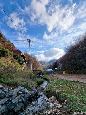 a small stream next to a road with a bench at APARTMAN NA STAZI - Bela Reka, Kopaonik in Brzeće