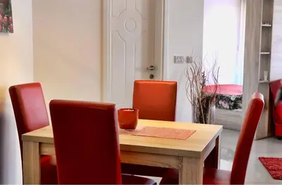 a dining room table with red chairs and a wooden table at LUX Apartmani Jagodina in Jagodina