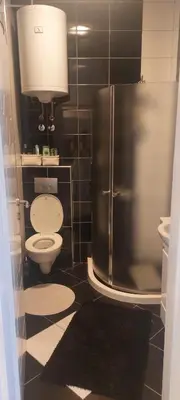 a bathroom with a toilet and a refrigerator at LUX Apartmani Jagodina in Jagodina
