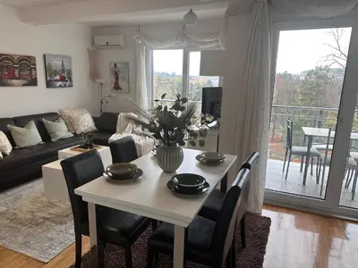 a living room with a table with chairs and a couch at Prelep Pogled, Elegantan Komfor Blizu Centra, Besplatan Parking, Apartman Floresta in Vrnjačka Banja
