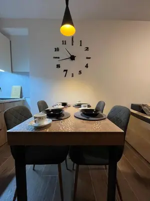 a dining room table with chairs and a clock on the wall at Apartments Myna in Kraljevi Cardaci in Kopaonik