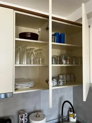 a kitchen cabinet filled with glass jars and dishes at Apartments Myna in Kraljevi Cardaci in Kopaonik