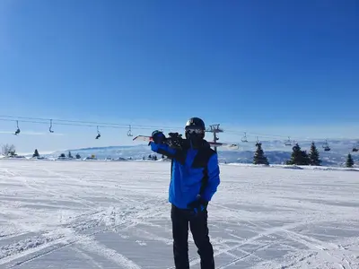 a man standing in the snow with a ski lift at Euphoria Milmari Resort Kopaonik in Kopaonik