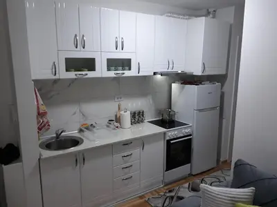 a kitchen with white cabinets and a sink and a refrigerator at Tanja Raj in Vrnjačka Banja