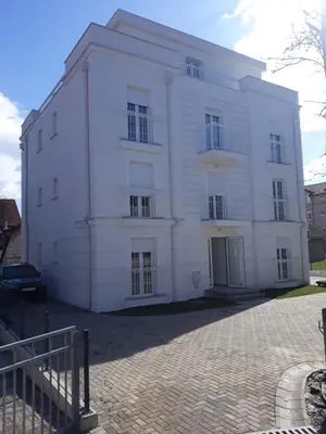 a large white building on a brick street at Tanja Raj in Vrnjačka Banja