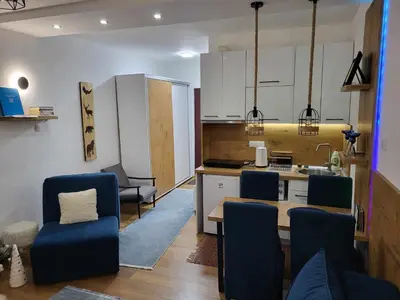 a kitchen with a table and chairs and a kitchen with white cabinets at Apartman Nina, Kopaonik, Brzeće, Kod Gondole in Brzeće