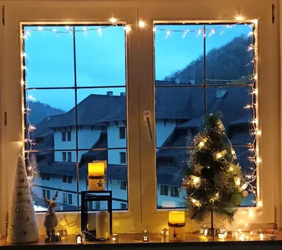 a christmas tree in front of a window with lights at Apartman Nina, Kopaonik, Brzeće, Kod Gondole in Brzeće