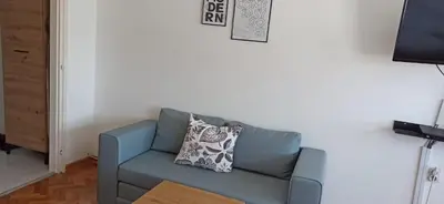 a blue couch in a living room with a pillow at City view - next to Delta Planet in Niš