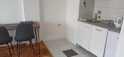 a kitchen with white cabinets and a table and chairs at City view - next to Delta Planet in Niš