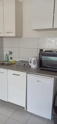 a kitchen with white cabinets and a sink and a microwave at City view - next to Delta Planet in Niš