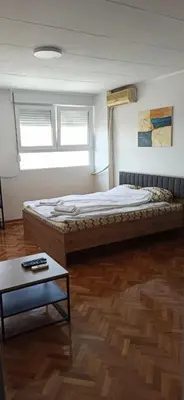 a bedroom with a bed and a table in it at City view - next to Delta Planet in Niš