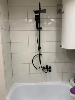 a shower with a hose attached to a white tiled wall at City view - next to Delta Planet in Niš