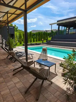 a patio with two chairs and a table next to a pool at Kucica na brdu in Zaječar