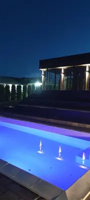 a swimming pool in front of a building at night at Kucica na brdu in Zaječar
