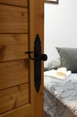 a black door handle on a wooden door with a bed at Vila MMBS in Brzeće
