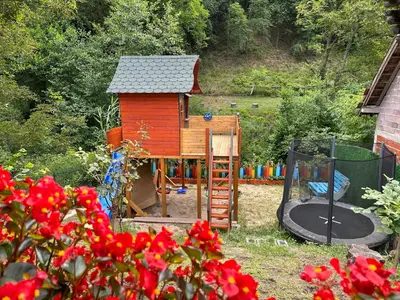 a small house with a playground in a garden at Etno kuća Trifunović in Pretrešnja