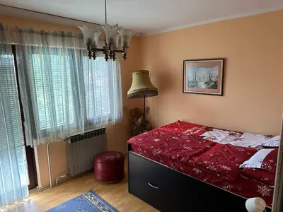 a bedroom with a bed with a red comforter at Etno kuća Trifunović in Pretrešnja