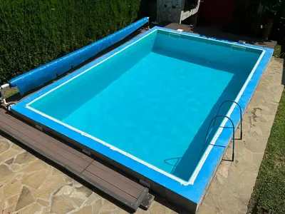 a blue swimming pool in the grass at Etno kuća Trifunović in Pretrešnja