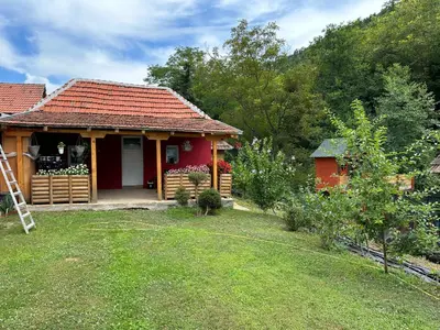 a red house with a yard and a house at Etno kuća Trifunović in Pretrešnja