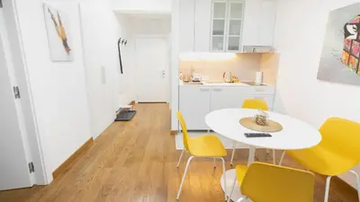 a kitchen and dining room with a white table and yellow chairs at Apartment miTski Kop in Kopaonik