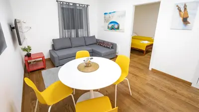 a living room with a white table and yellow chairs at Apartment miTski Kop in Kopaonik
