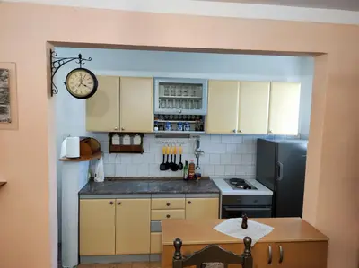 a kitchen with a refrigerator and a clock on the wall at Panonka apartman in Leskovac