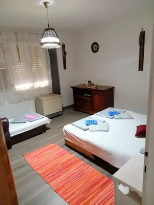 a bedroom with two beds and a table and a chandelier at Panonka apartman in Leskovac