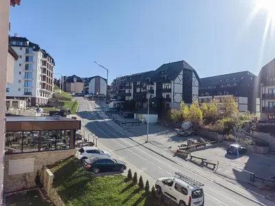 a city street with cars parked on the road at White Apartman Kopaonik in Kopaonik