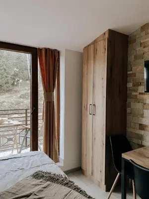 a bedroom with a bed and a table and a window at Zlatokosina zona Kopaonik Milmari NLux in Kopaonik
