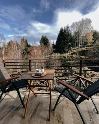 a wooden table and two chairs on a deck at Zlatokosina zona Kopaonik Milmari NLux in Kopaonik