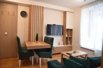 a living room with a table and chairs and a tv at Apartman LUCIJA 9D57 Kraljevi Cardaci in Kopaonik