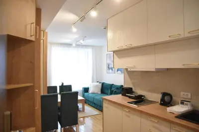 a kitchen and living room with a blue couch at Apartman LUCIJA 9D57 Kraljevi Cardaci in Kopaonik