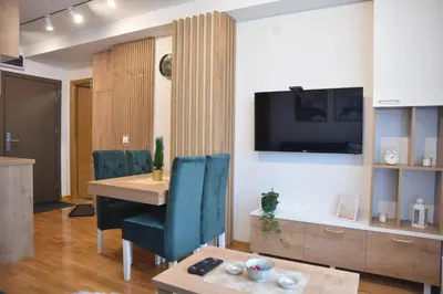 a living room with a table and a tv on a wall at Apartman LUCIJA 9D57 Kraljevi Cardaci in Kopaonik