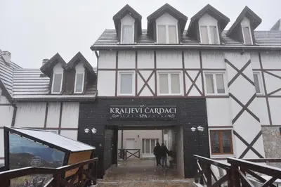 a white and black building with people walking into it at Apartman LUCIJA 9D57 Kraljevi Cardaci in Kopaonik