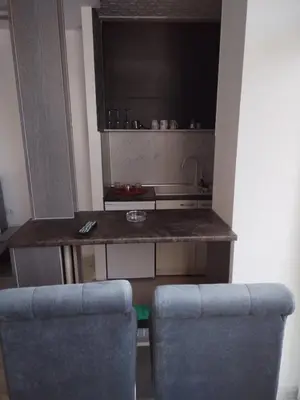 a kitchen with a counter and two blue chairs at VIN Studio in Kruševac