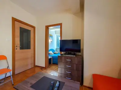 a living room with a television on a dresser with a couch at Apartman Cvejic - Suncani apartmani in Brzeće