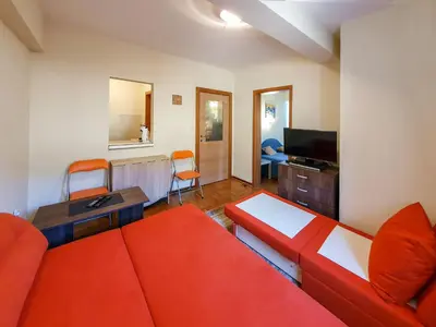 a living room with a red couch and a television at Apartman Cvejic - Suncani apartmani in Brzeće
