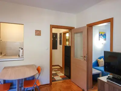 a small living room with a table and a television at Apartman Cvejic - Suncani apartmani in Brzeće