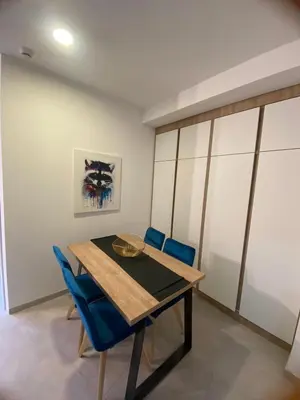 a dining room with a wooden table and blue chairs at Apartmani Srna Milmari in Kopaonik