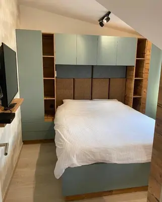 a bedroom with a white bed and a flat screen tv at Apartmani Srna Milmari in Kopaonik